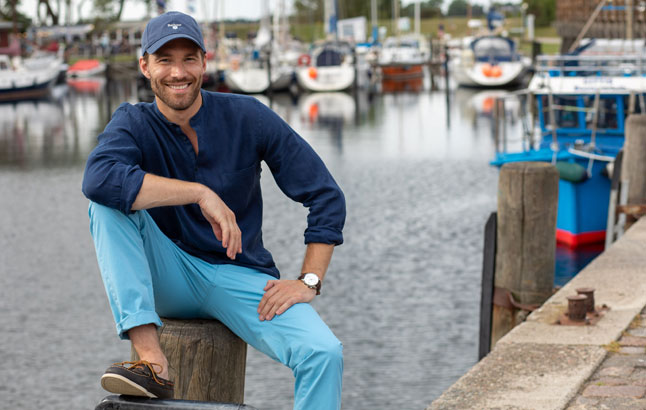 Mann hockt an Hafenkante Sportboothafen