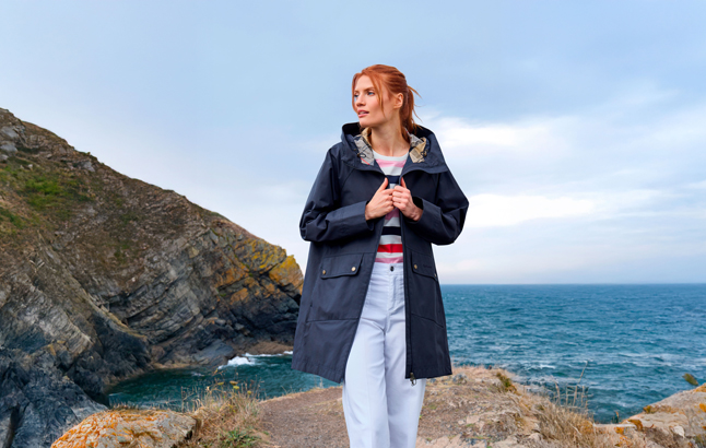 Frau in Barbour-Jacke an Küste