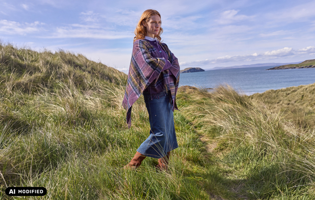 Frau mit Plaid an Küste