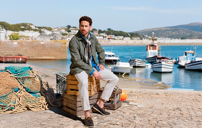 Mann sitzt auf Kisten am Strand