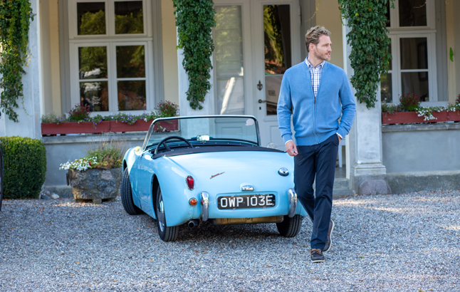 Mann in Strickjacke vor Oldtimer