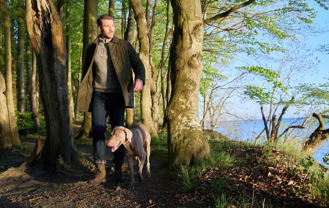 Mann wandert mit Jagdhund durch den Wald