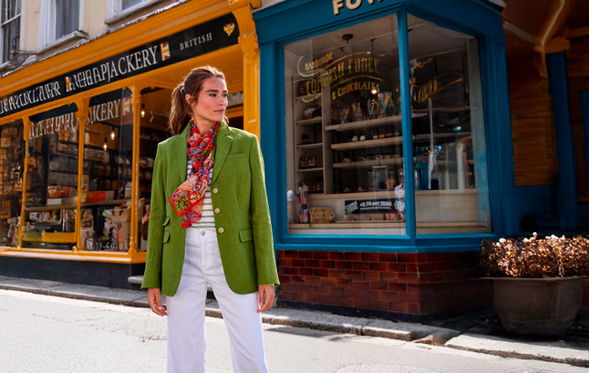 Frau vor Ladenzeile im grünen Blazer