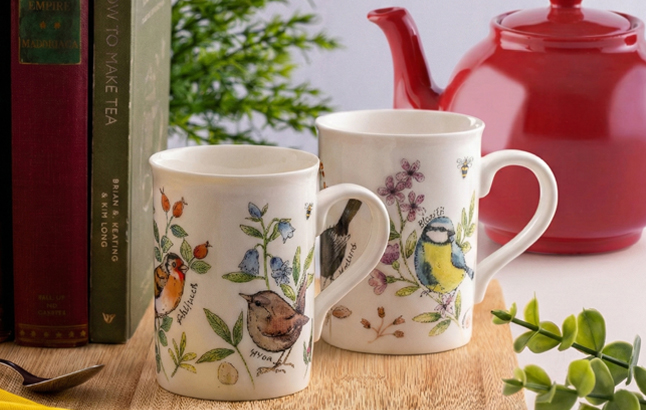 Porzellanbecher mit klassisch englischer Teekanne im Hintergrund